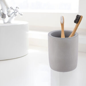Minimalist gray toothbrush holder on a white sink