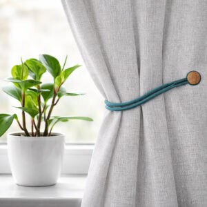 Magnetic Curtain Tieback Holding Gray Curtain – A teal magnetic tieback securing a gray curtain near a window.
