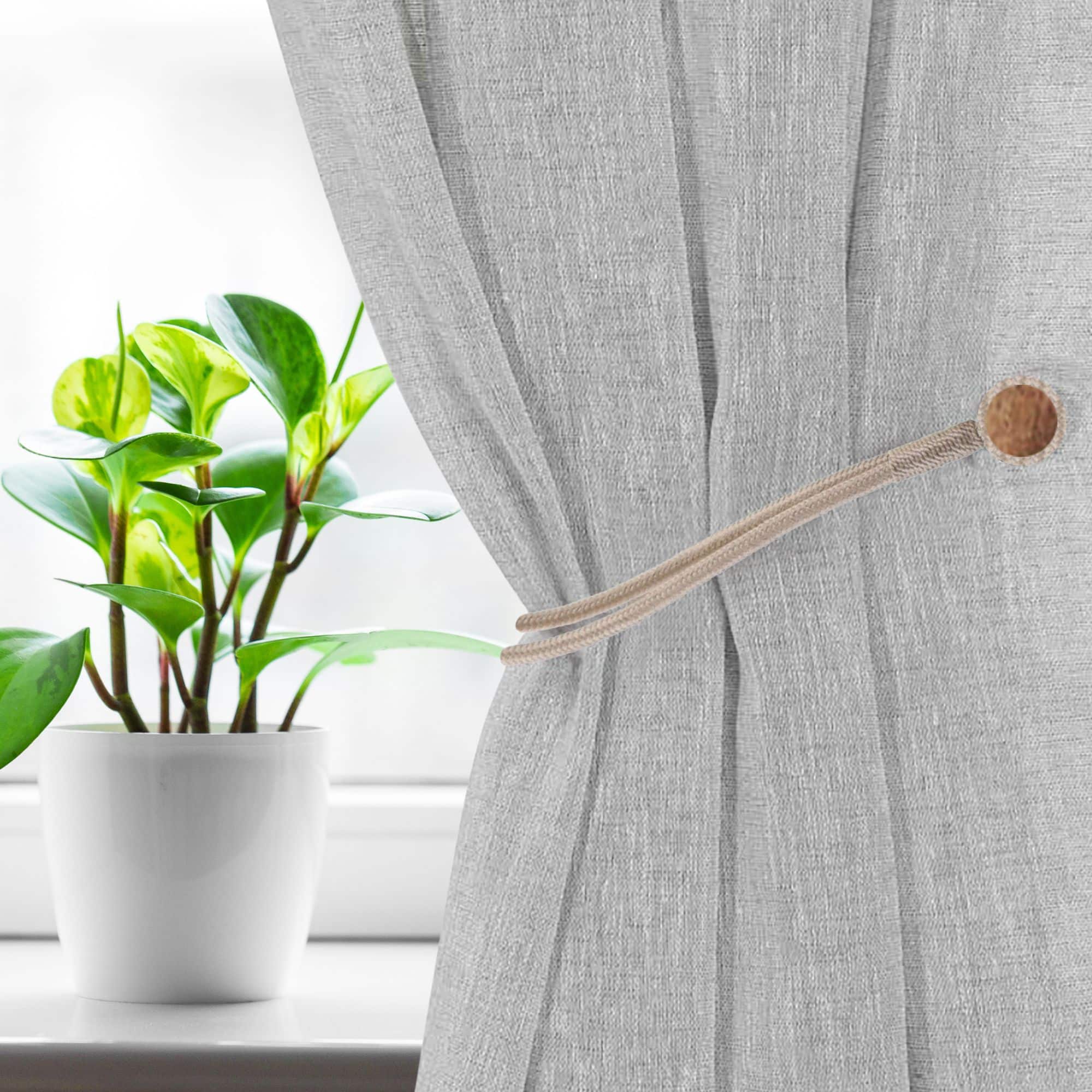 Beige magnetic tieback holding a gray curtain