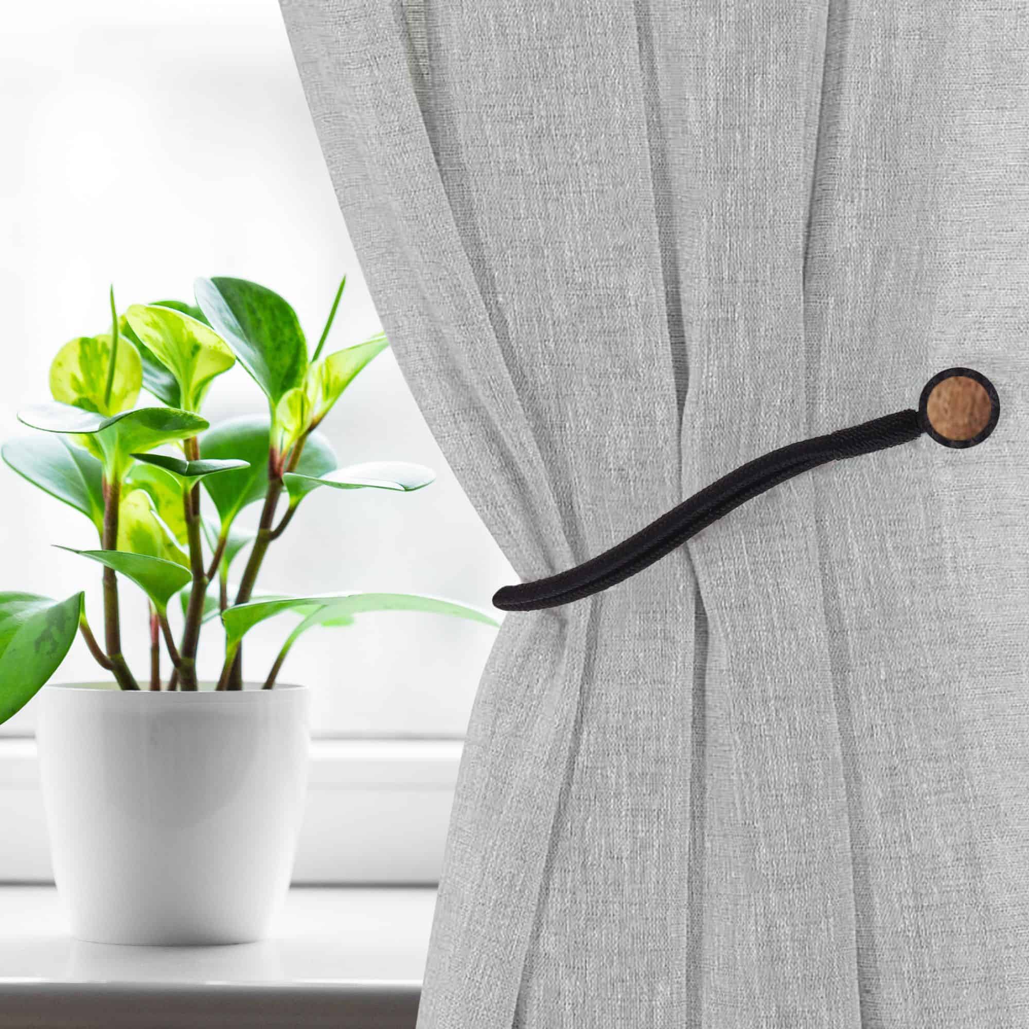 Magnetic Curtain Tieback Holding Gray Curtain – A black magnetic tieback securing a gray curtain near a window.