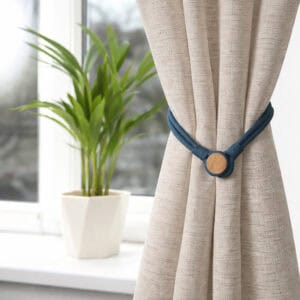 Magnetic Curtain Tieback in Beige Curtain – A teal magnetic tieback securing a beige curtain near a window with a potted plant.