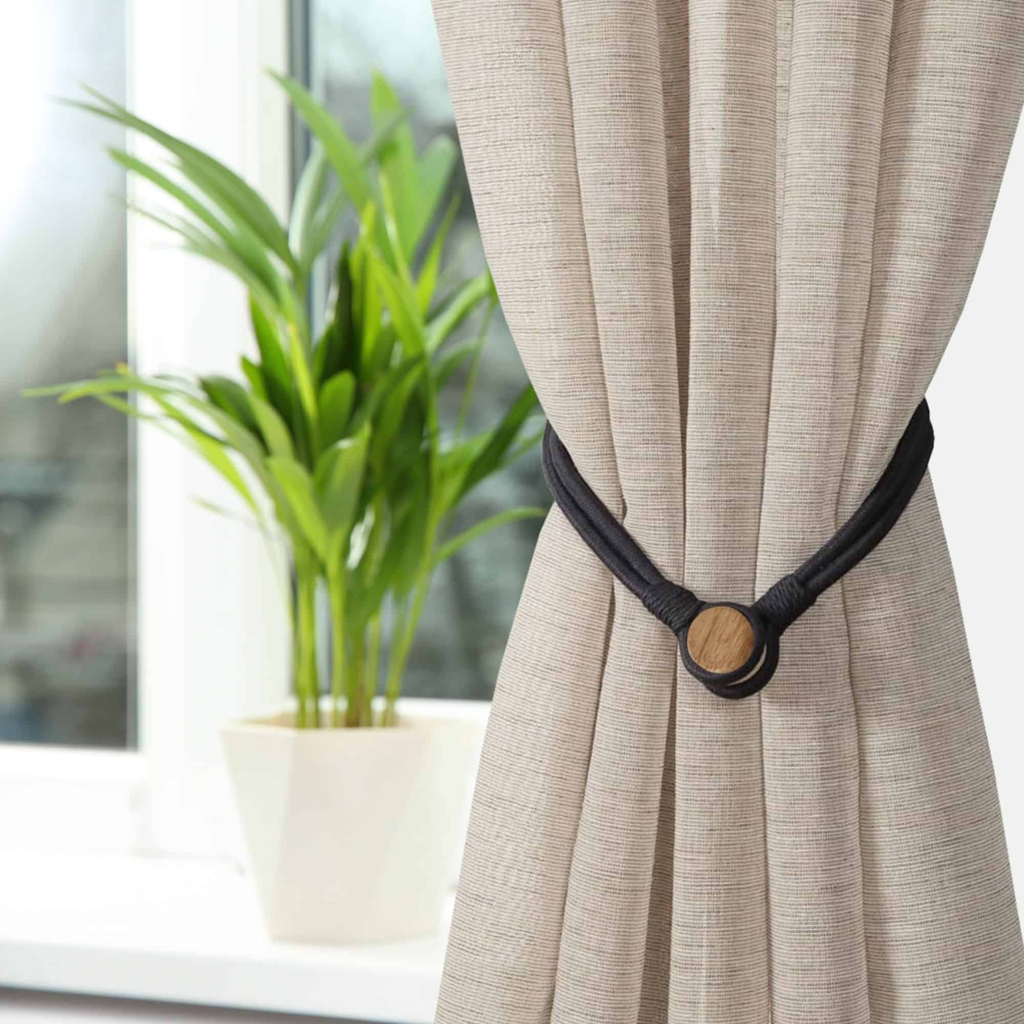 Black magnetic curtain tieback securing a beige curtain