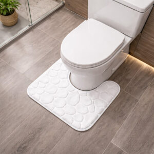 White memory foam contour bath mat with pebble texture positioned around toilet base, angled view