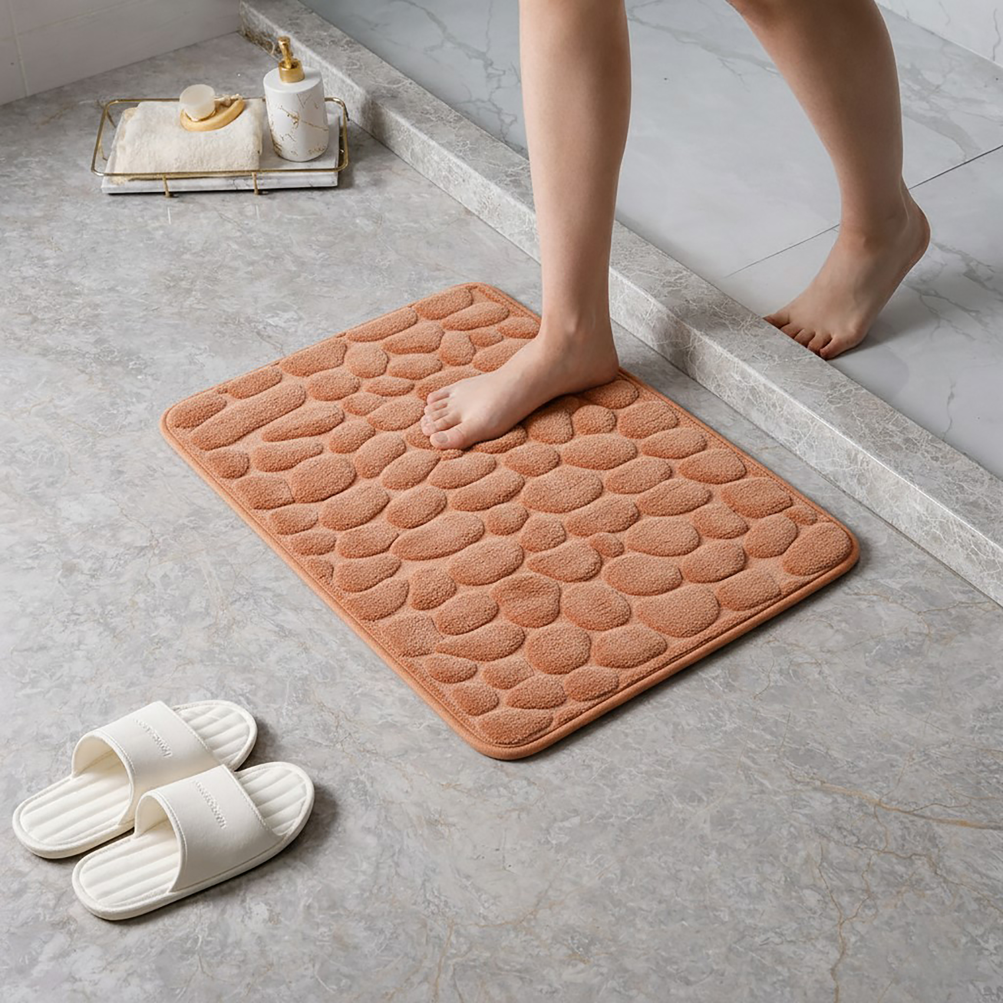 Barefoot stepping on a soft copper pebble design memory foam mat placed on a bathroom tile floor