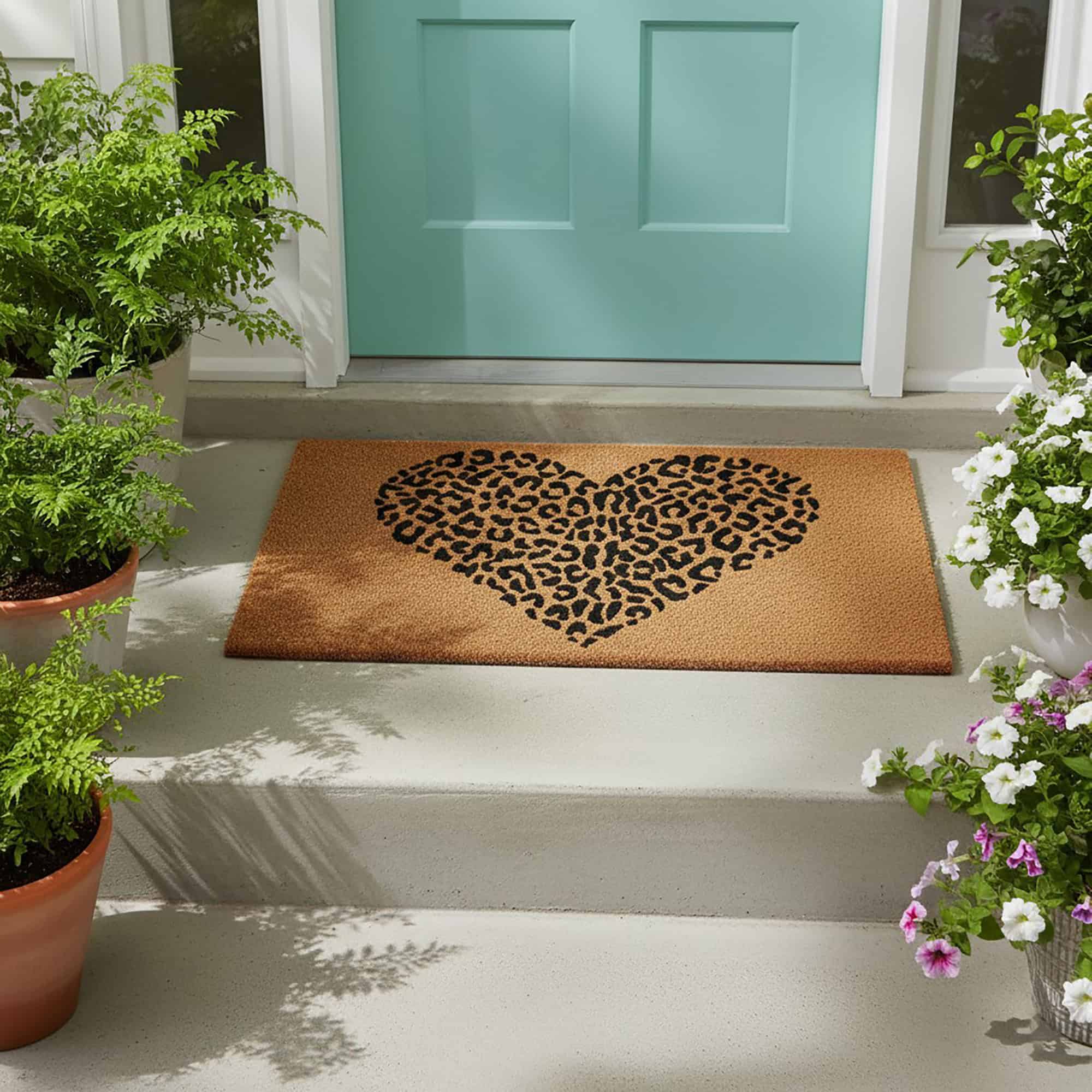 Leopard print heart coir doormat at teal front door with flowers and plants