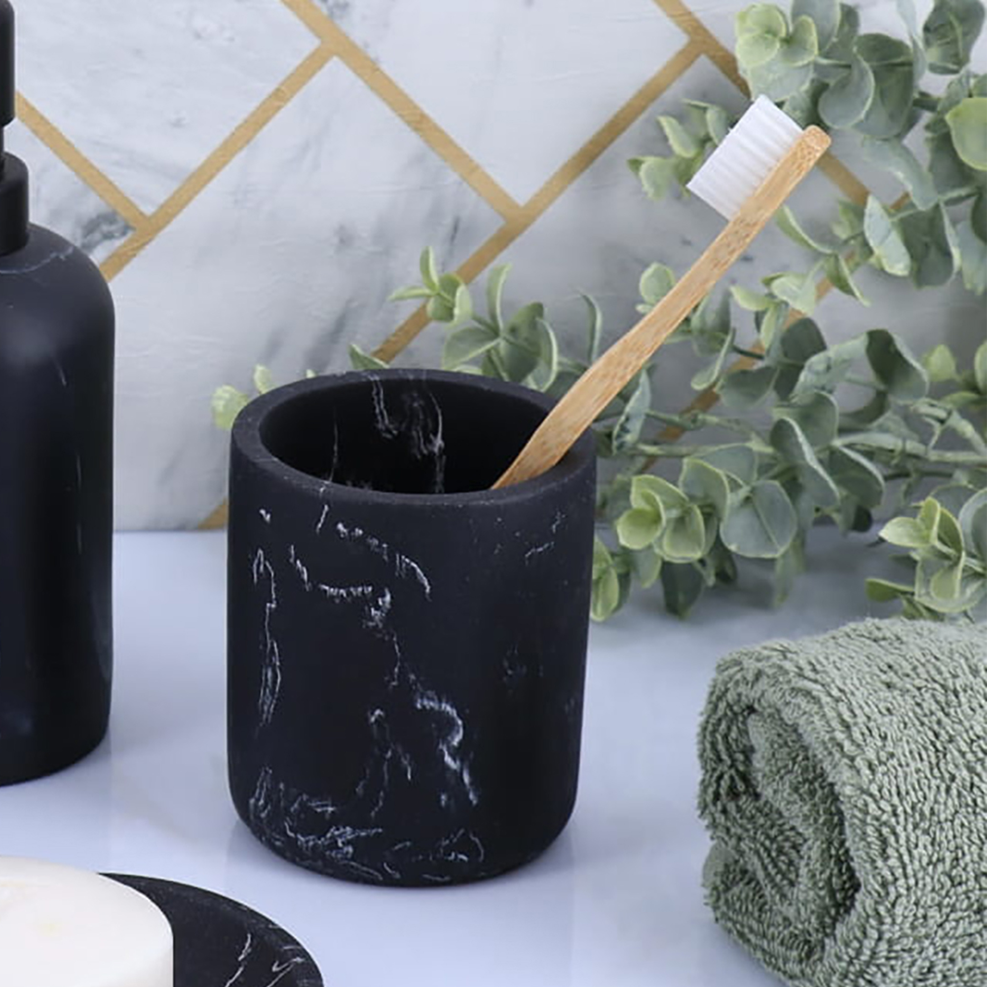 Black marble tumbler toothbrush holder with bamboo toothbrush on countertop