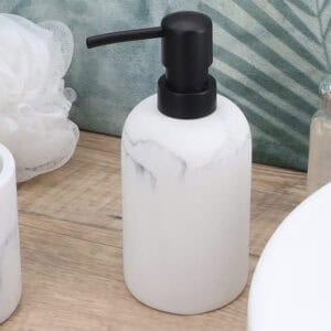 White marble soap dispenser with black pump on bathroom vanity near sink