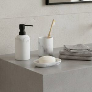 White marble soap dispenser with black pump displayed with tumbler soap dish and folded towels