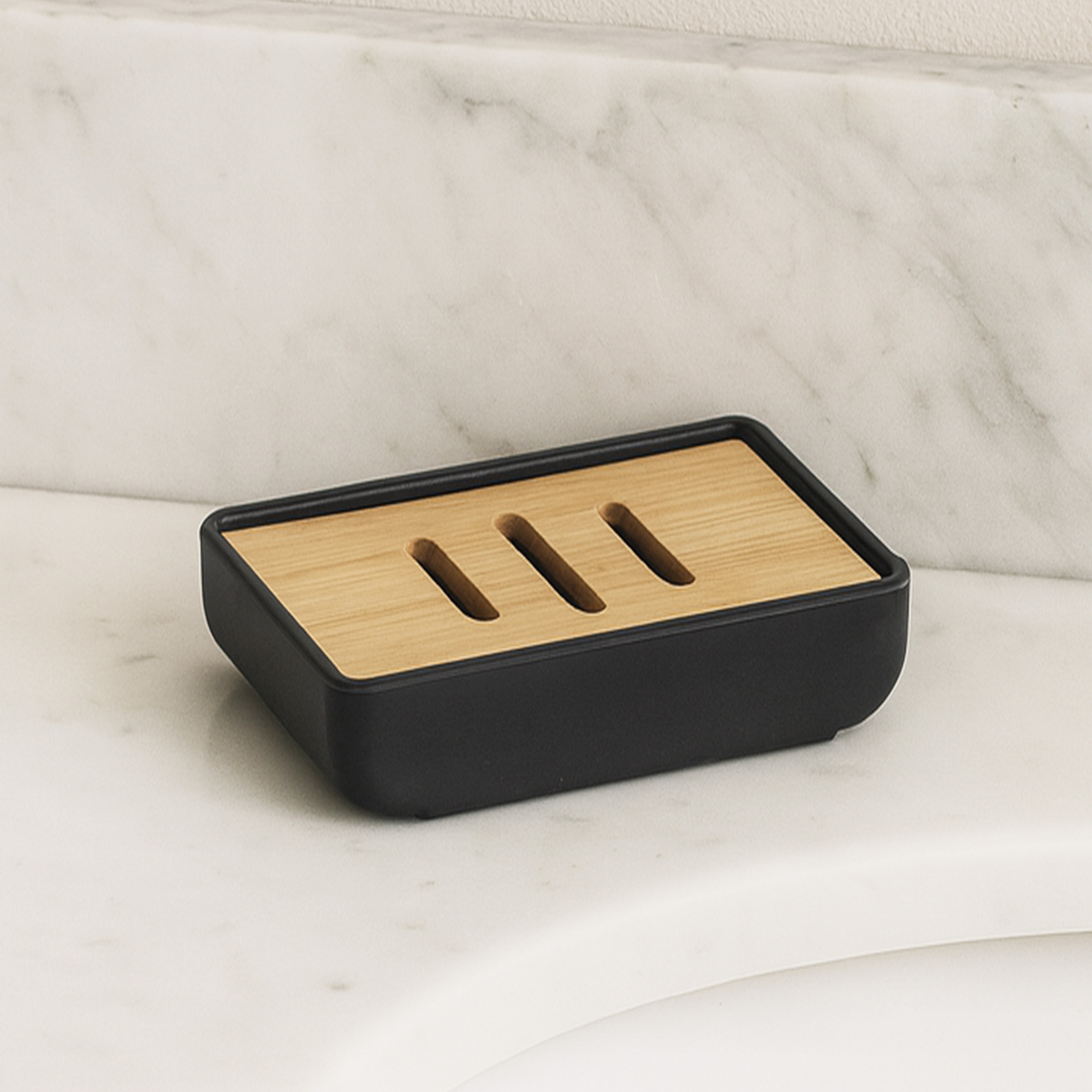 Black rubber soap dish with bamboo slotted tray shown empty on marble surface