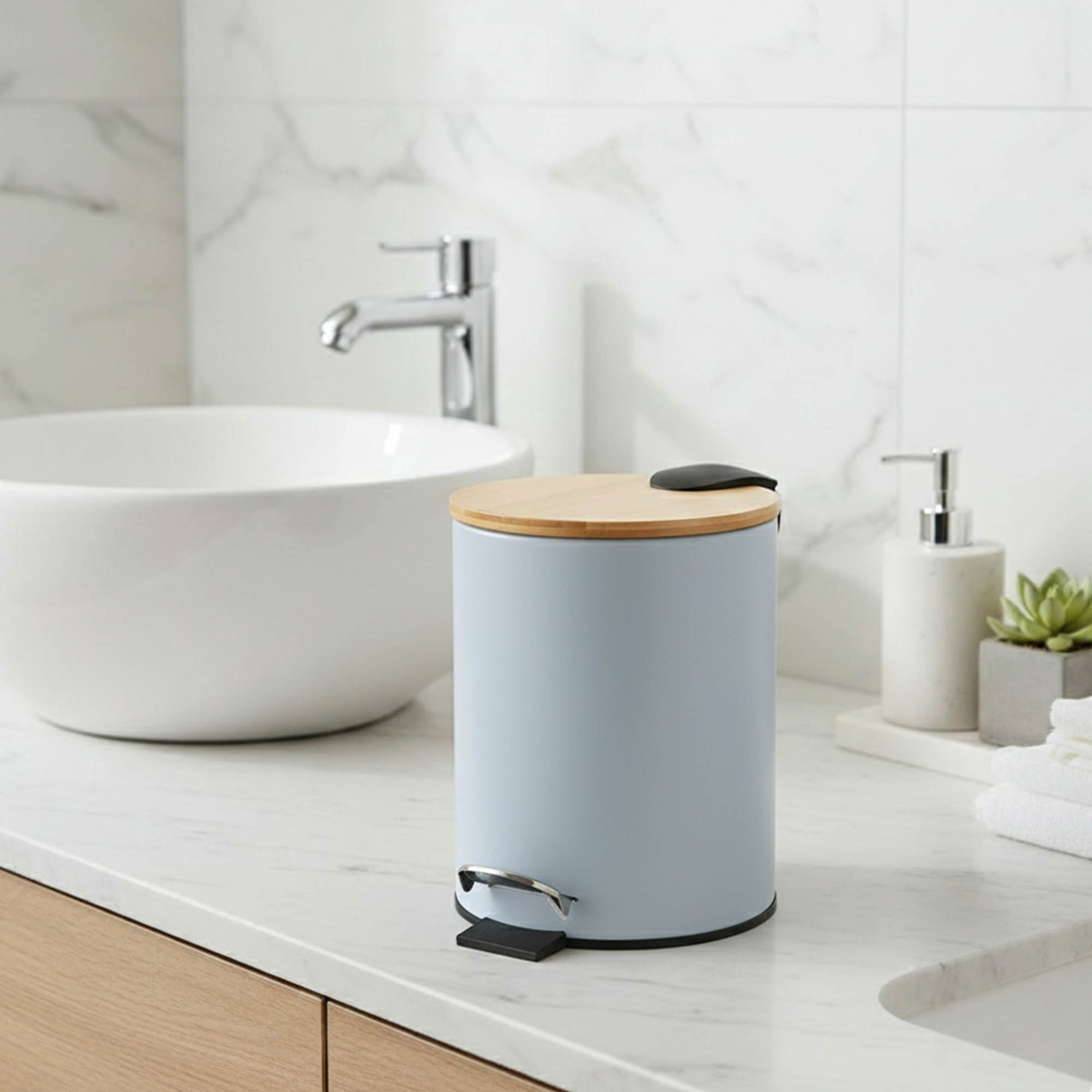 Light blue step trash can with bamboo lid on bathroom countertop