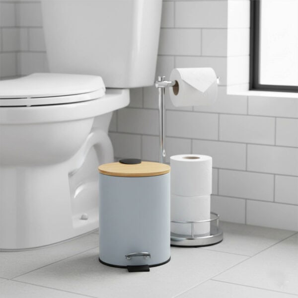 Light blue step trash can with bamboo lid next to toilet