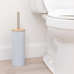 "Light blue toilet brush holder with bamboo lid and steel handle beside white toilet"