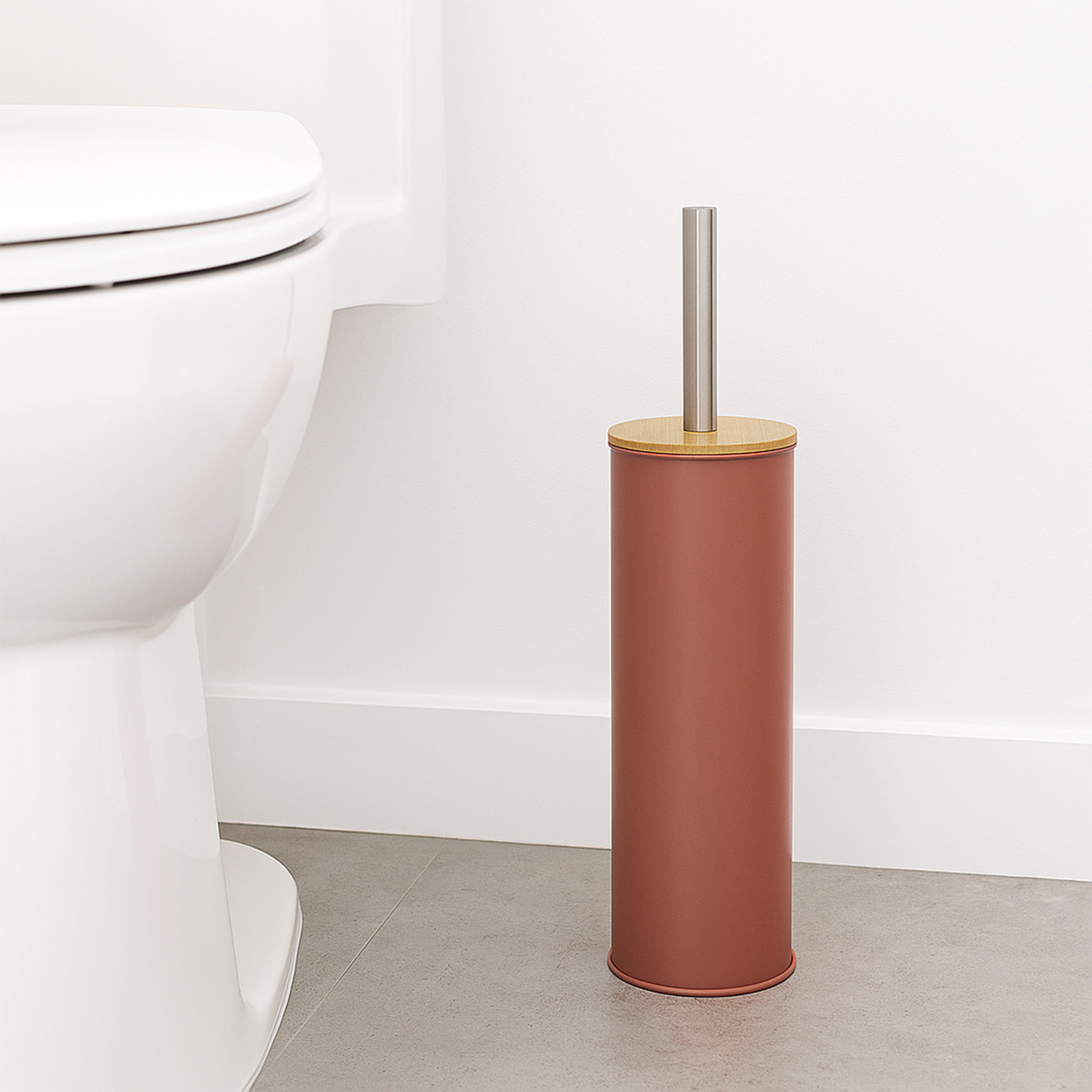 "Terracotta toilet brush holder with bamboo lid and steel handle beside white toilet"