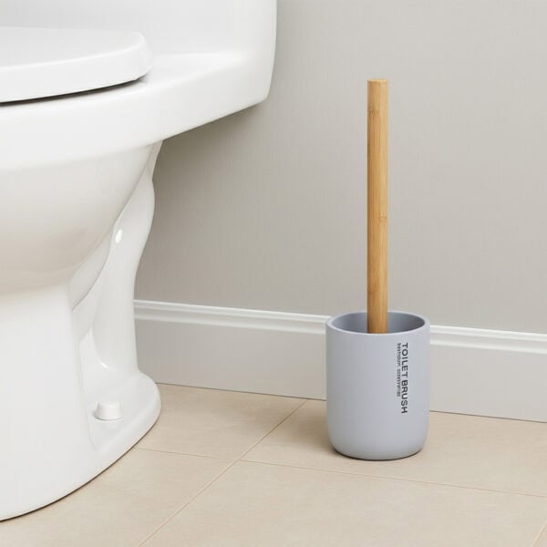 Light blue toilet brush with bamboo handle in matching holder placed beside toilet