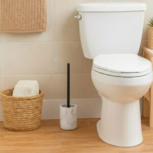 White marble toilet brush holder with black handle beside white toilet in modern bathroom