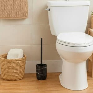 Black marble toilet brush holder with black handle beside white toilet in modern bathroom