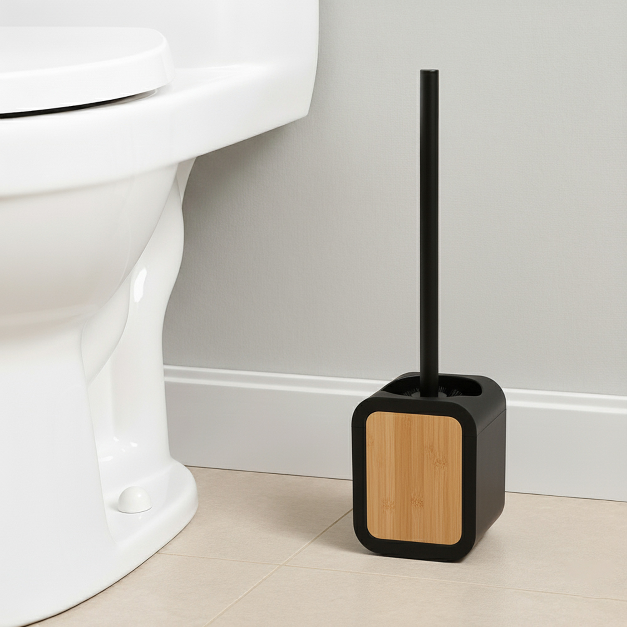 Black toilet brush holder with bamboo insert and black handle beside white toilet