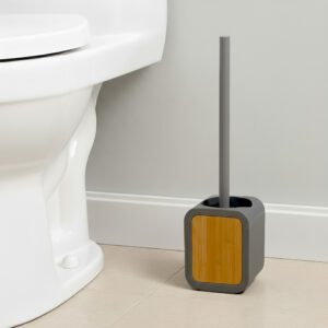 Gray toilet brush holder with acacia wood panel and gray handle beside white toilet