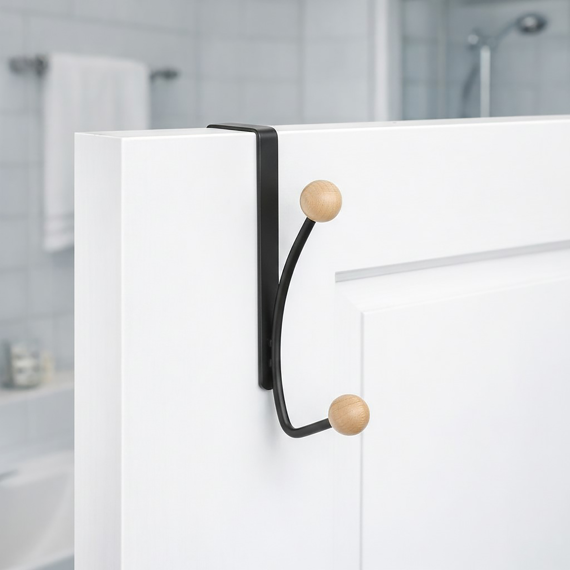 "Matte black double hook with wood ball ends mounted on white bathroom door"