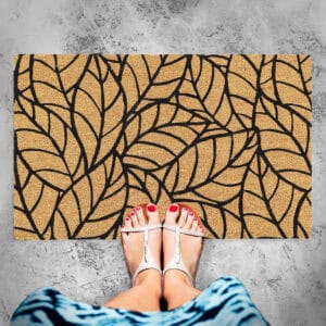 Coir entry mat featuring a bold leaf pattern in black on natural brown coir