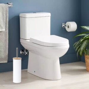 White toilet brush in clean bathroom with blue walls, beside white toilet