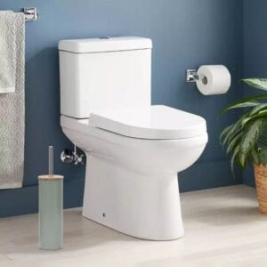 Green toilet brush placed in clean bathroom with blue walls, next to white toilet