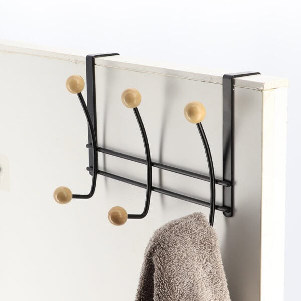 "Matte black double-hook over-the-door rack with wood ball ends holding brown towel on door"