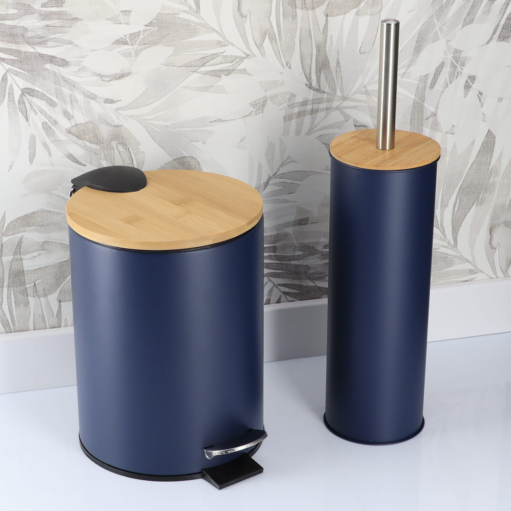 Navy blue bathroom trash bin and toilet brush holder in a bathroom with patterned wall background