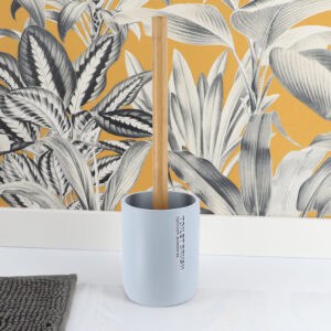 Toilet brush with bamboo handle and light blue holder against yellow botanical wallpaper