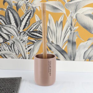 Toilet brush with bamboo handle in cappuccino holder placed against yellow botanical wallpaper