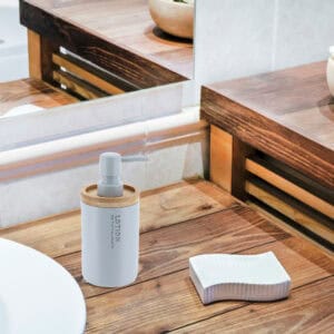 Matte light blue soap dispenser on rustic wood countertop with mirror