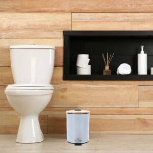 Compact light blue bin with foot pedal next to toilet in bathroom