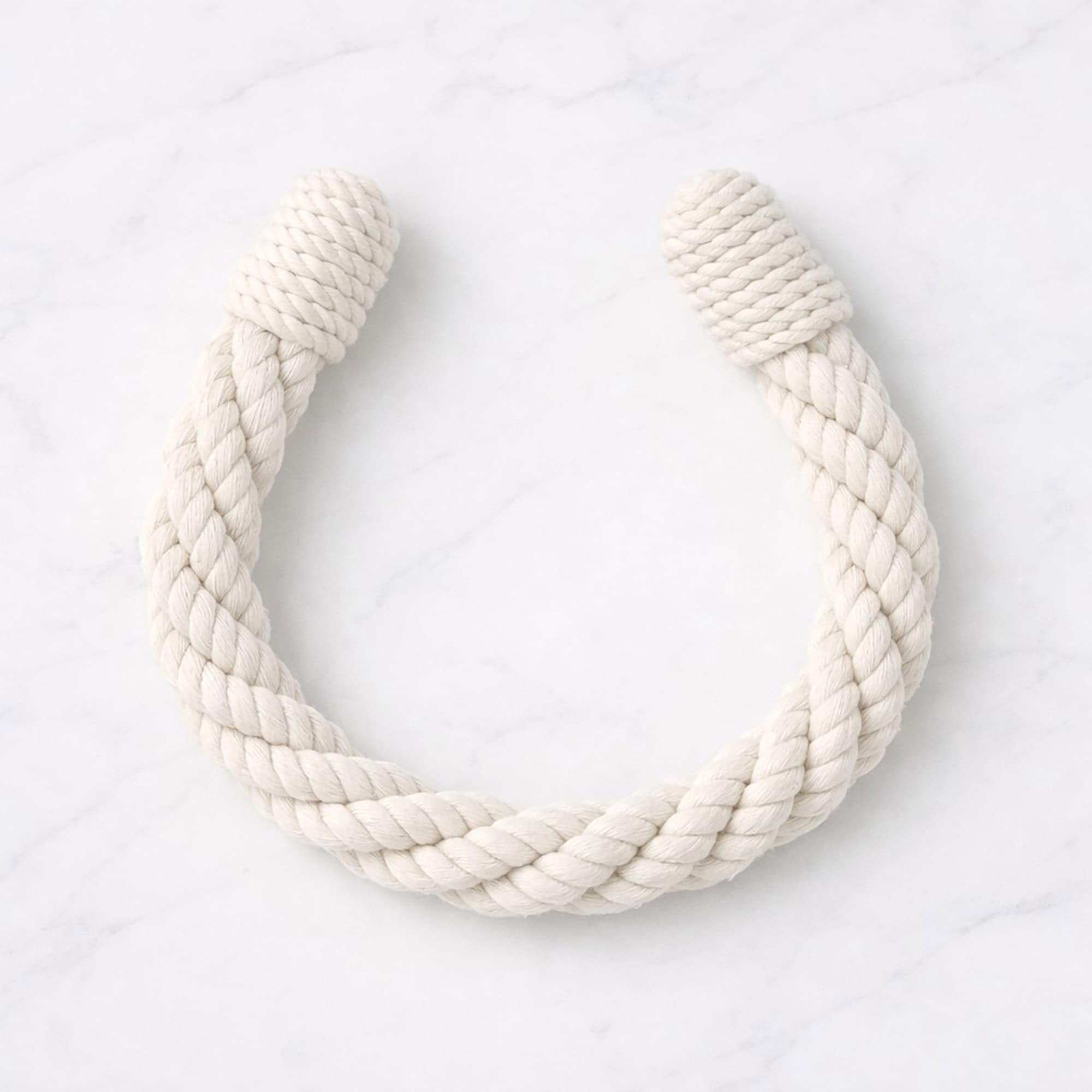 "Chalk white twisted rope tieback in U-shape on marble surface"