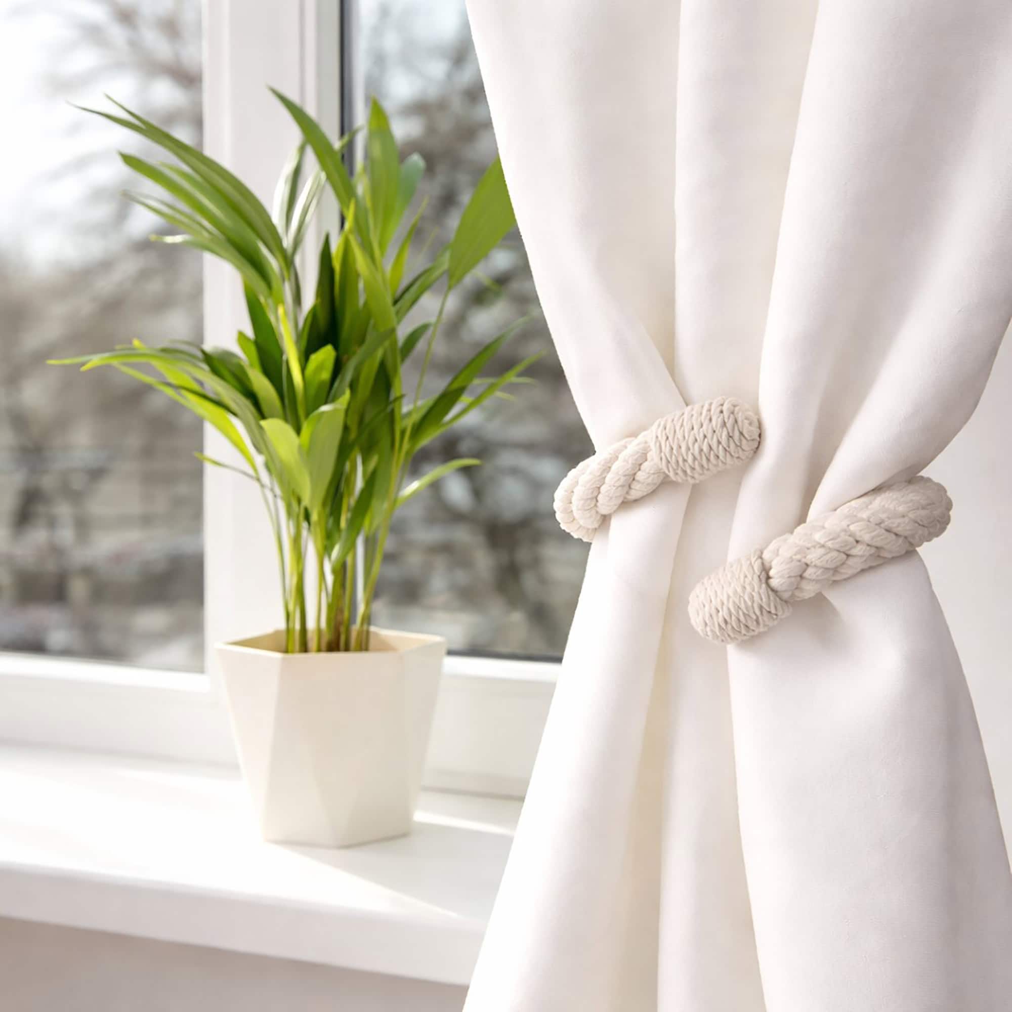 "Cotton rope tieback on white curtain beside a potted plant on a windowsill"