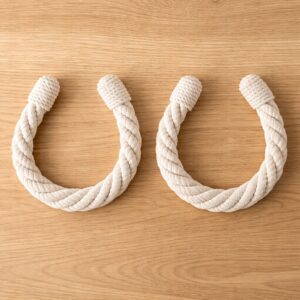 "Chalk white twisted rope tiebacks in U-shape on wooden surface"