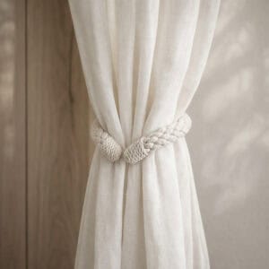 "Cotton rope tieback holding a gathered sheer curtain against a wood-toned wall"