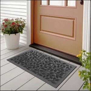 Black rubber doormat placed at front door with flowers and siding