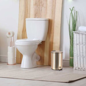 Brushed gold trash can next to white toilet in modern bathroom setup