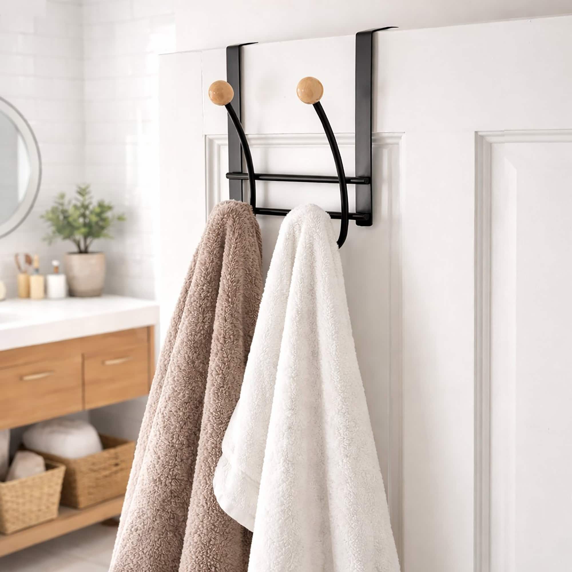 Black over-the-door hook rack with 4 natural ball hooks, holding a beige and a white towel on a white bathroom door.