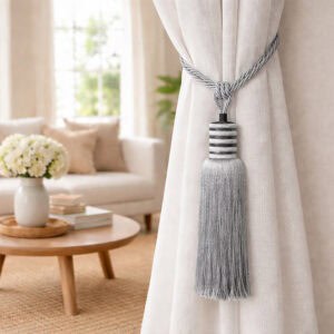 Close-up of a silver mist curtain tieback with twisted rope loop and tassel holding a white sheer curtain