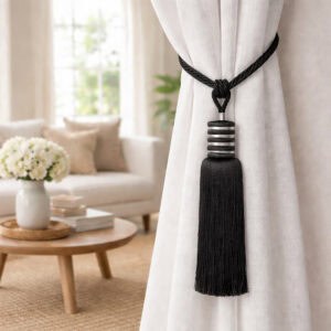Close-up of a midnight black curtain tieback with twisted rope loop and tassel holding a white sheer curtai