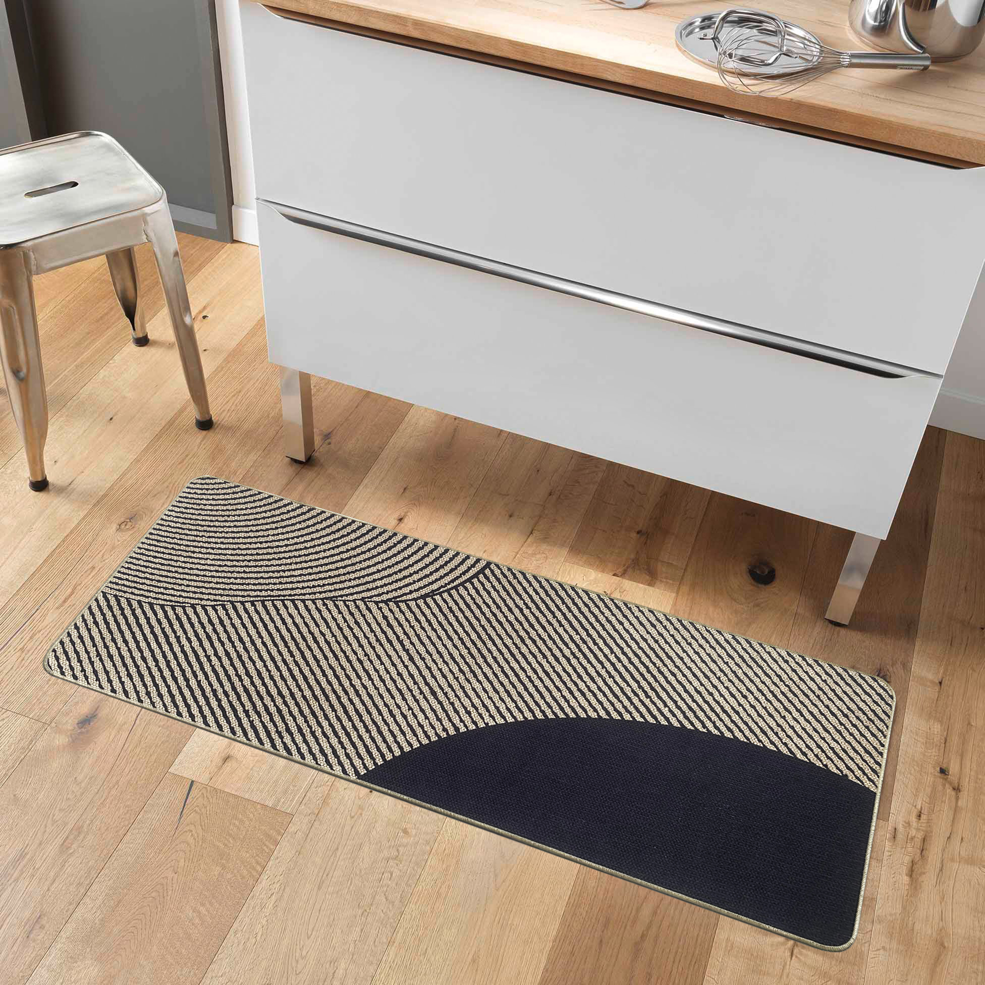 Kitchen runner mat placed on wood floor beside white cabinets with a modern metal stool