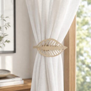 Champagne gold leaf curtain tieback holding back a white sheer panel against a wood frame