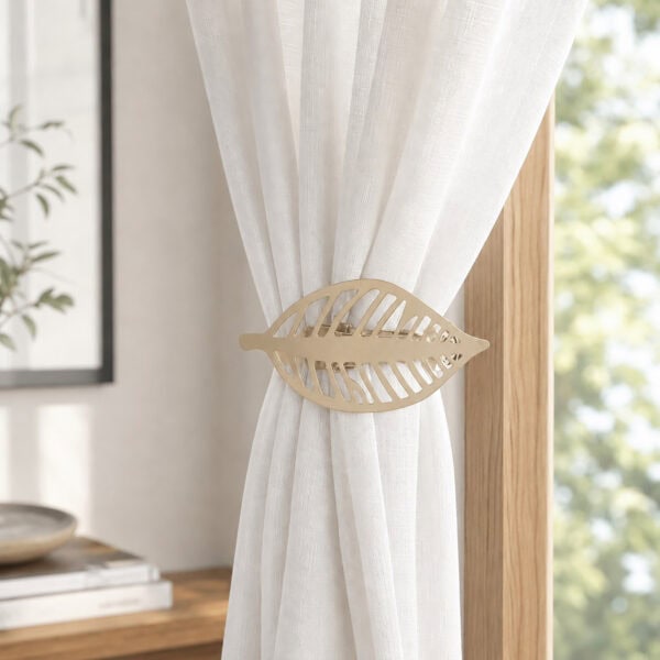 Champagne gold leaf curtain tieback holding back a white sheer panel against a wood frame