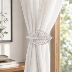 Whitewash leaf curtain tieback holding back a white sheer panel against a wood frame