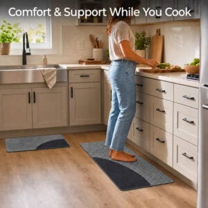 Person standing comfortably on a gray kitchen mat while a matching runner sits nearby, cushioned support for cooking and cleanup tasks.
