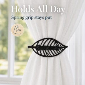 Textured black leaf curtain tieback with spring grip holding gathered sheer fabric
