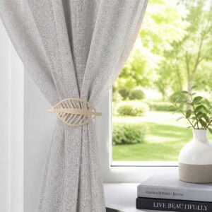 Champagne gold leaf curtain tieback on a gray sheer panel by a sunny window with a vase