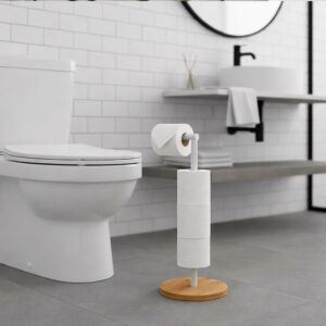 "White freestanding toilet paper holder with bamboo base holding 4 rolls, next to toilet in modern white bathroom"