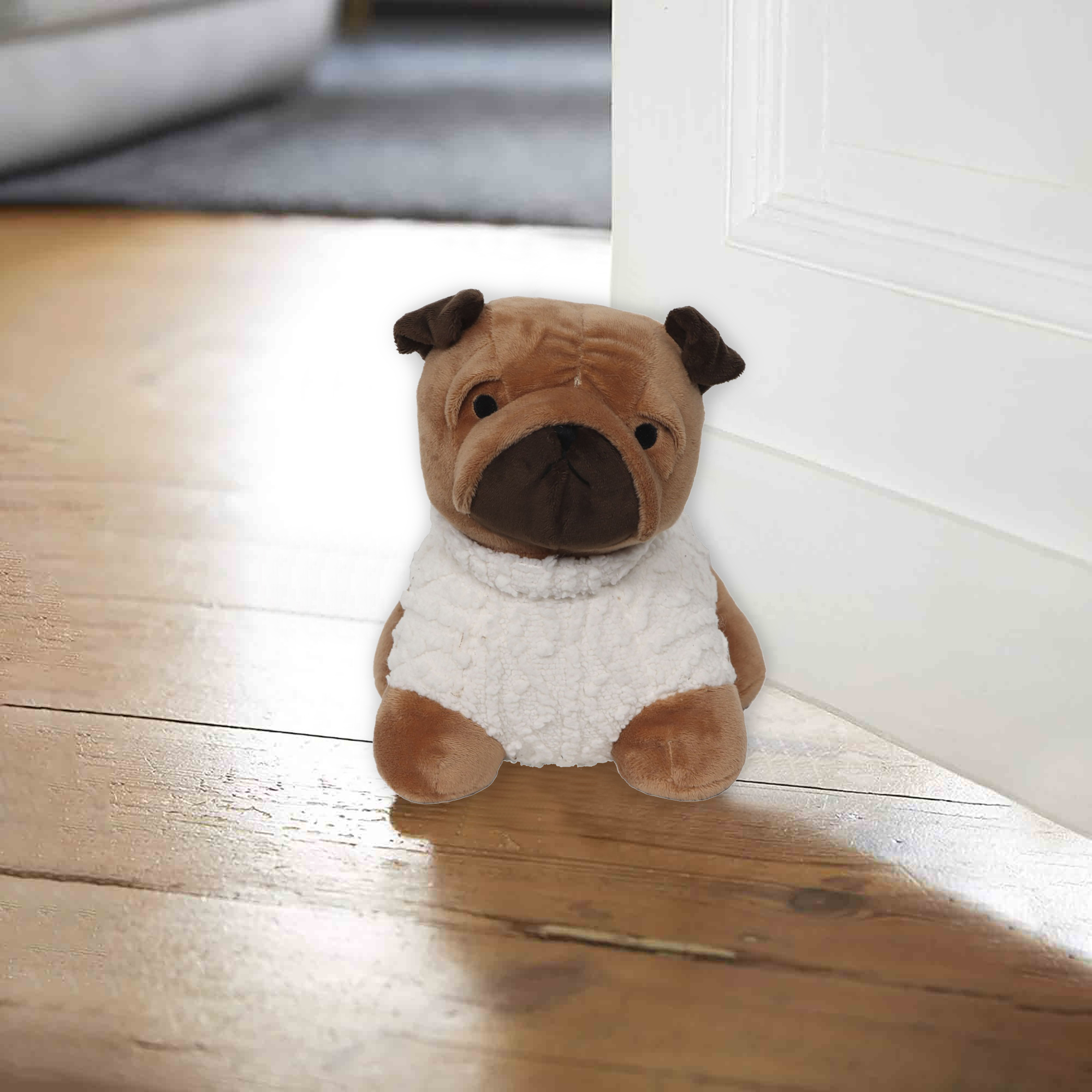 Stuffed pug door stopper placed between white door and wooden floor